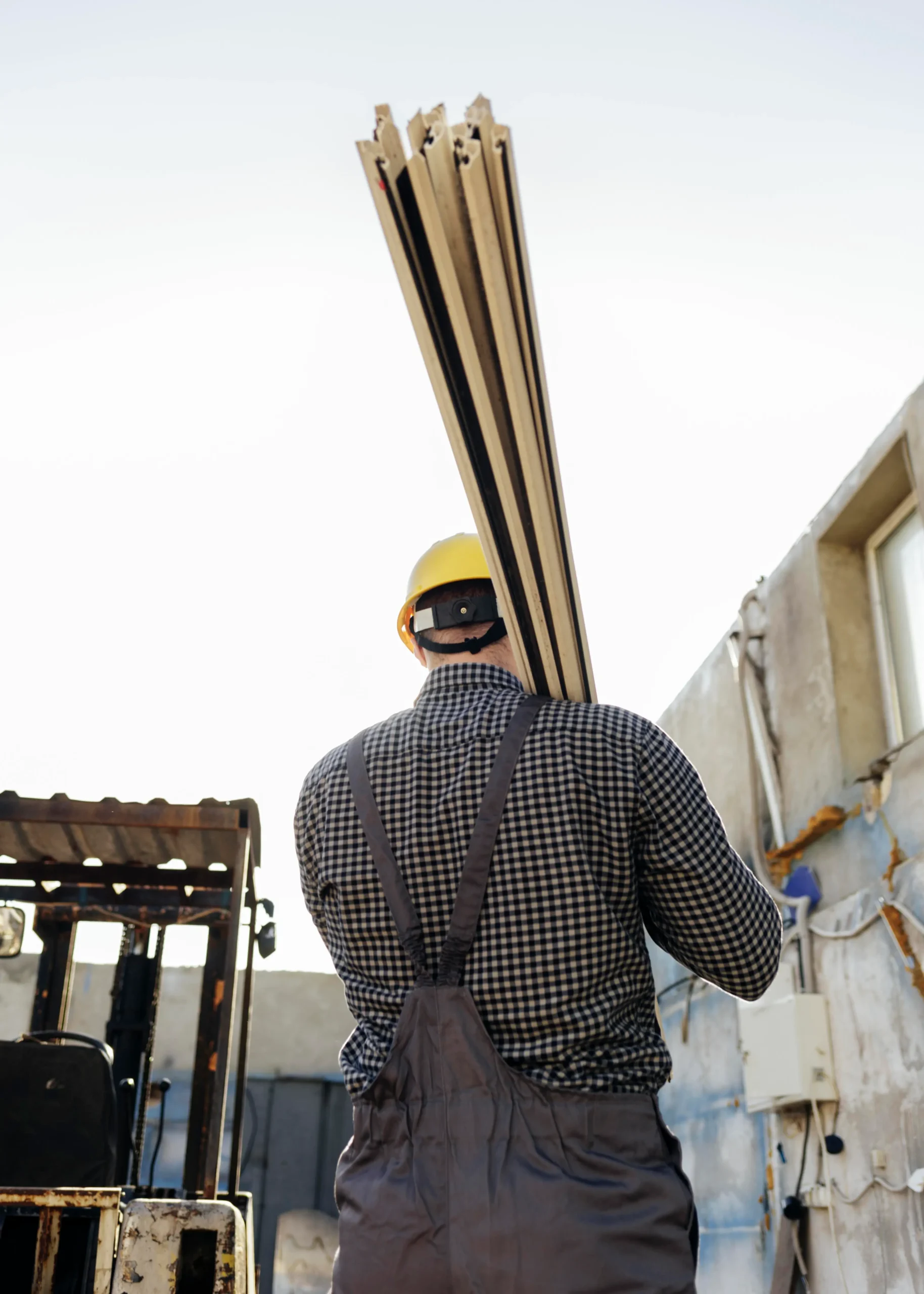 Back view of a construction worker carrying timber